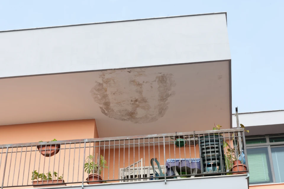 Façade d'immeuble résidentiel avec importantes taches d'humidité et infiltrations d'eau sur mur extérieur