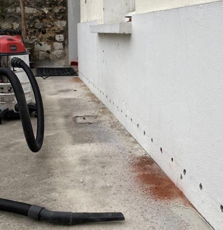 Un technicien en combinaison sombre et bonnet travaille sur le pare-brise d'un véhicule dans un atelier automobile